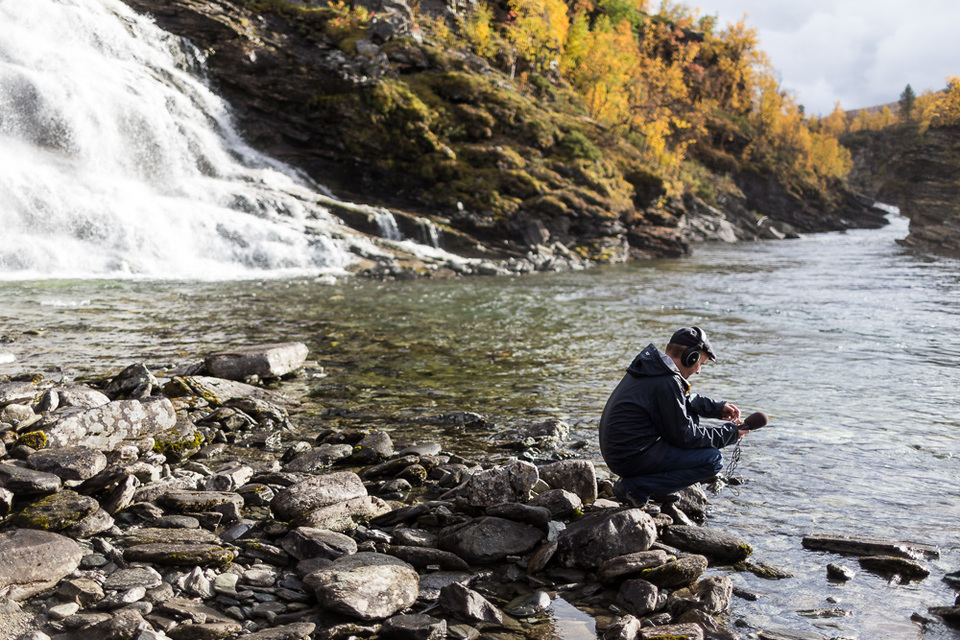 A scientist captures a soundscape recording near a waterfall