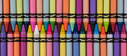 dozens of crayons of different colors lined up tip to tip.